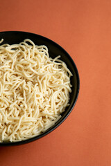 egg noodle in a black bowl on a brown background