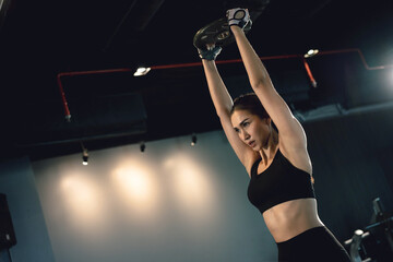 Sporty woman exercising with weight plate in the gym.