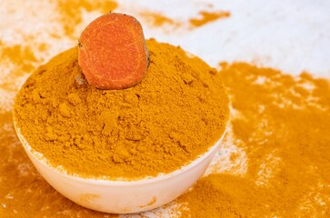 Turmeric Powder in a White Bowl with Turmeric Root Isolated on White Background with Copy Space