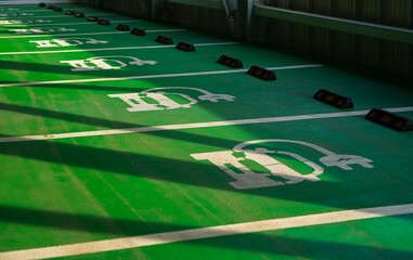 Special green parking places for electricity powered vehicles in a public parking. Electric cars industry.