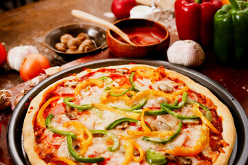 Homemade Italian pizza, mixed vegetables, cheese and bacon, fresh out of the oven. Placed on a dark wooden floor. Top view. Fast food concept.