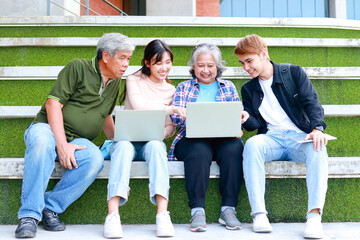 Group of university students of different ages smiling happily using laptop computers to learn....