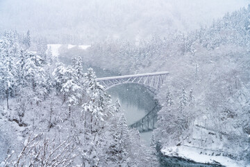 Aerial view Landscape of Railway bridge between the mountain over the river in snow day. Pine tree forest mountain with railroad track covered in snow. Beautiful scenic nature in winter season.