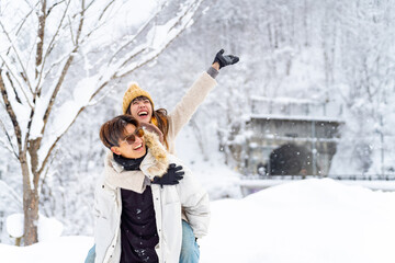 Asian couple have fun during travel small town and forest mountain covered in snow together on...