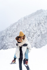 Asian couple have fun during travel small town and forest mountain covered in snow together on...