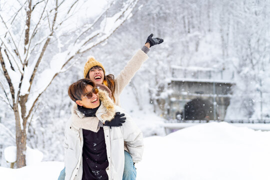Asian couple have fun during travel small town and forest mountain covered in snow together on winter holiday vacation. Man and woman enjoy outdoor lifestyle travel local village in Japan in snowy day
