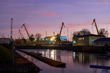 Fototapeta na wymiar Port cranes stand near the sea docks. Maritime communication in the time of Covid