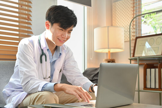 Smiling male doctor communicating distantly with patient or giving online consultation for domestic health treatment on laptop 