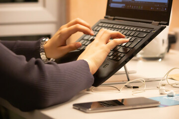young girl works at computer, typing something on laptop keyboard. selective focus on hands, noise include.