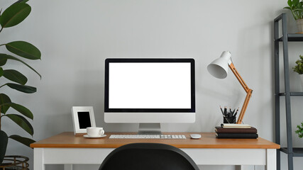 Home office desk with blank screen computer monitor and supplies on wooden table. Blank screen for graphic display montage