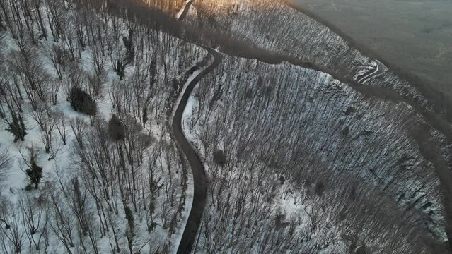Aerial view of a serpentine road crossing a forest in wintertime with snow on Mount Terminio, Serino, Avellino, Irpinia, Campania, Italy.