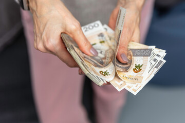 Kobieta trzyma w dłoniach banknoty, pieniądze polskie, złotówki. Liczenie pieniędzy. - obrazy, fototapety, plakaty