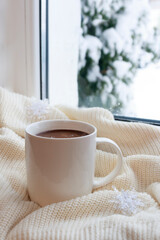 Cozy winter still life: a mug of hot coffee and a warm blanket. warming drink for a winter morning