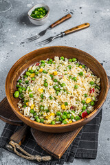 Chinese Fried rice with egg and vegetables in a wooden plate. Gray background. Top view