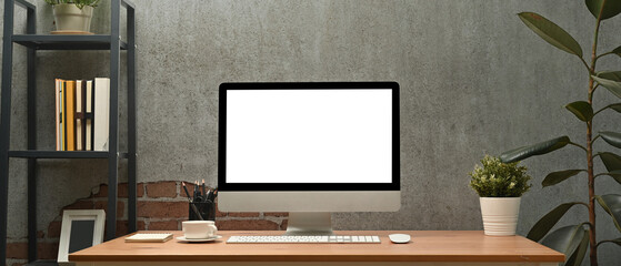 Stylish workplace white blank screen computer monitor on wooden desk. Blank screen for graphic display montage