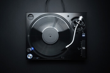 Flat lay photo of DJ turntable playing vinyl record on black background. Professional analog record...