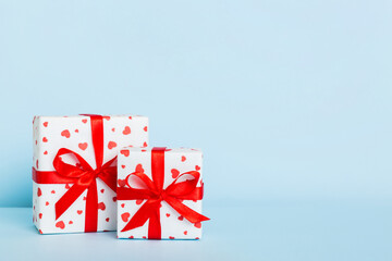 gift box with red bow and red heart on colored background. Perspective view. Flat lay
