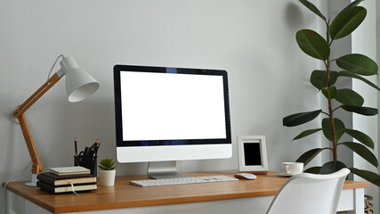 Modern workplace with blank computer screen, lamp and supplies on wooden desk. Empty screen for your advertising design