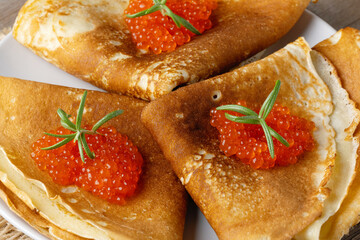 Stack of russian thin pancakes blini with red caviar on an old wooden table. Maslenitsa,...
