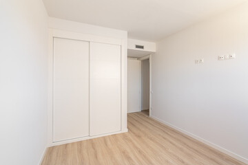 White empty sunny room with built-in wardrobe ventilation and two doors to the bathroom and exit. Concept of a new building or real estate for rent