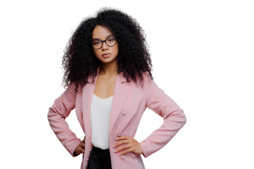 Photo of serious curly haired woman looks confidently at camera, wears formal neat clothes, keeps both hands on waist, wears optical glasses, poses over purple background. People, style concept