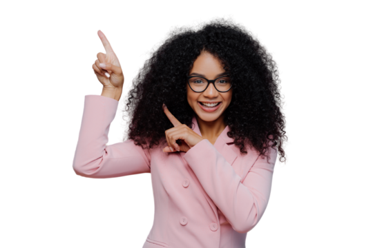 Half length shot of cheerful Afro American woman with dark bushy hairstyle, wears violet suit, points above with both index fingers, demonstrates way to something, invites you going upstairs