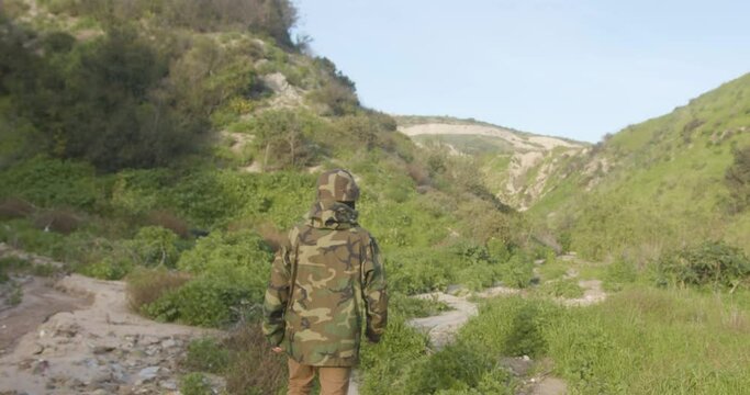 militar caminando en la jungla encapuchado.sicario