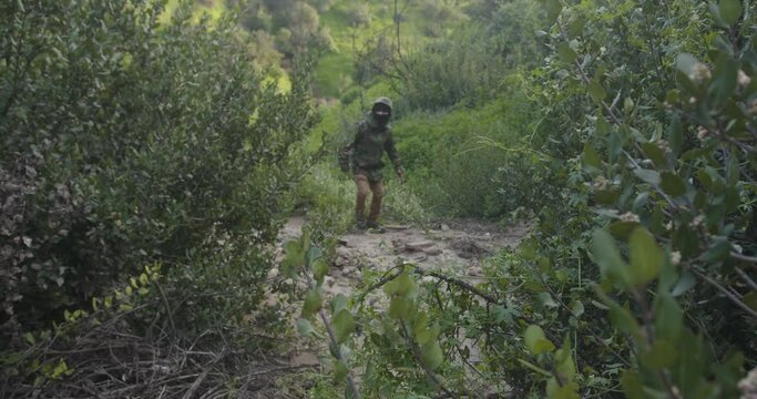 militar caminando en la jungla encapuchado. sicario