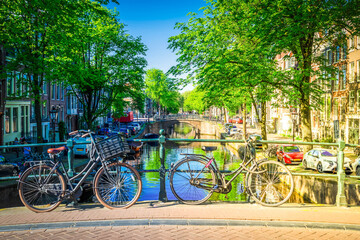 Fototapeta na wymiar Orange bicycle next to canal of Amsterdam