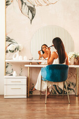 brunette woman with long straight dark hair and clean skin doing make up routine