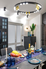 A modern living room with a blue sofa and a fixed table. Ceiling with wooden beams. Open space