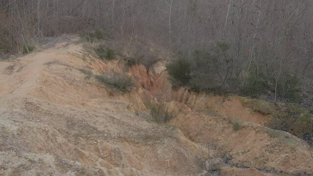 zoom out and panning on a deep gully in a slope of red clay
