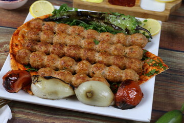 Close up of Skewered Beef Kebab Serving Plate with Grilled Tomato Onion and Pepper Slices