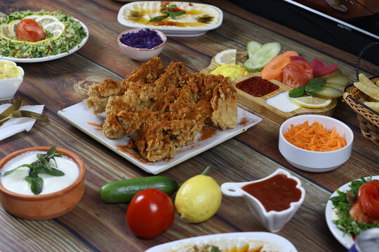 Exquisite and Artistic Image of Chicken Dish Dinner on Wooden Table with Side Dishes, Garnishes and Dips