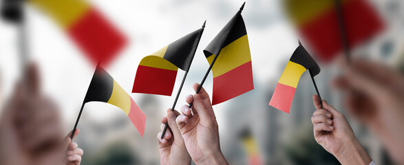 A group of people holding small flags of the Belgium in their hands