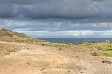 Desert landscape of yellow sand and green grass, with storm clouds in Abades, Tenerife, Canary Islands. Spain