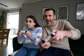 Caucasian teenager girl with dad playing at video game
