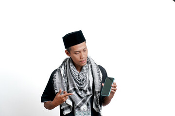 Religious muslim asian man wearing turban, muslim dress and cap. Pointing at the smartphone screen, feeling happy, surprised or calm. isolated on white background.