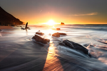 Sunset while sea waves hitting the rocks on the beach; at Ilbarritz beach in Biarritz, Basque Country.