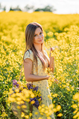 Naklejka na ściany i meble Portrait of a beautiful girl in yellow rapeseed flowers