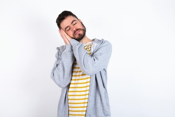 caucasian man wearing casual sportswear over white wall sleeping tired dreaming and posing with hands together while smiling with closed eyes.