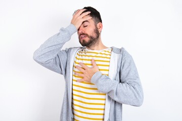 caucasian man wearing casual sportswear over white wall Touching forehead for illness and fever,...