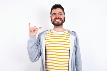 Fototapeta premium caucasian man wearing casual sportswear over white wall showing up number six Liu with fingers gesture in sign Chinese language