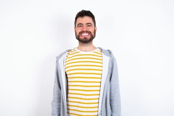 Fototapeta premium caucasian man wearing casual sportswear over white wall with nice beaming smile pleased expression. Positive emotions concept
