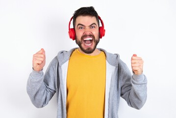 Emotional caucasian man wearing casual sportswear oexclaims loudly feels like winner raises...