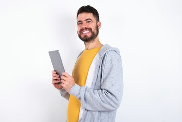 Photo of optimistic caucasian man wearing casual sportswear over white wall hold tablet