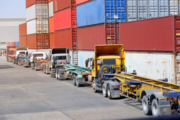 Trucks in a logistics yard with containers stacked in the background.