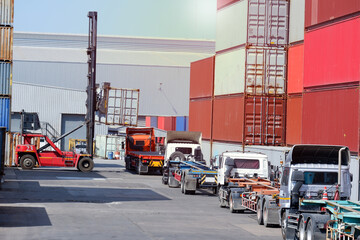 Forklifts, containers and trucks In the logistics yard with containers stacked in the background