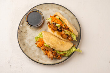 Steamed bao buns with chicken and vegetables in a plate, top view two pieces.