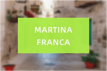 Martina Franca: Der Name der italienischen Stadt Martina Franca in der Region Puglia vor einem Hintergrundbild - obrazy, fototapety, plakaty